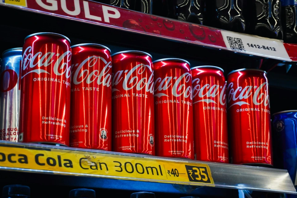 Several red coca-cola cans on a shelf